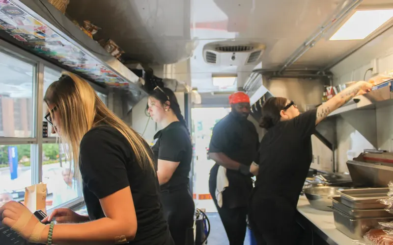 Four cooks working the line inside the Cream City mobile kitchen, one at the service window